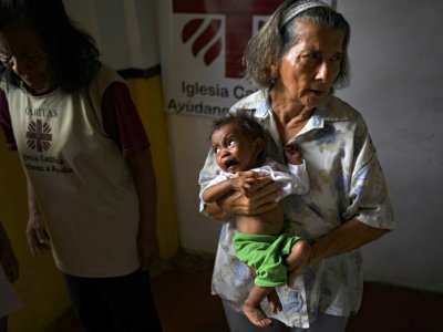 Une employée de l'organisation caritative Caritas porte un bébé Yukpa dans ses bras à la mission d'El Tucuco, le 12 juin 2019 au Venezuela - YURI CORTEZ [AFP]