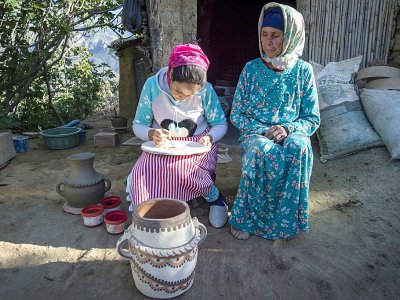 La potière Houda Oumal (g) peint une poterie avec des pigments naturels à côté de sa mère Fatima Harama, le 11 juin 2019 près de Ourtzagh, au Maroc - FADEL SENNA [AFP]
