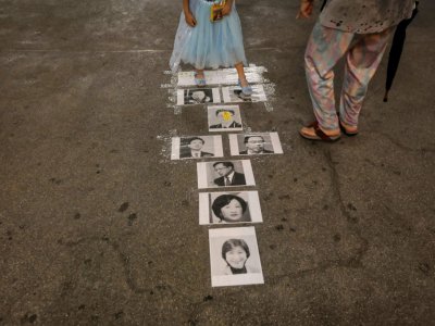 Une jeune fille joue à la marelle sur les portraits d'hommes politiques favorables à la Chine, à Hong Kong le 10 juillet 2019 - VIVEK PRAKASH [AFP]
