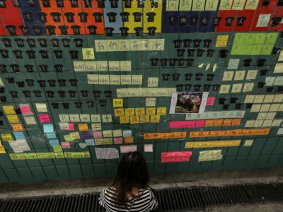 Une femme ajoute un post-it sur un mur affichant des messages de protestation contre le gouvernement et le projet de loi favorisant l'extradition vers la Chine, à Hong Kong le 10 juillet 2019 - VIVEK PRAKASH [AFP]
