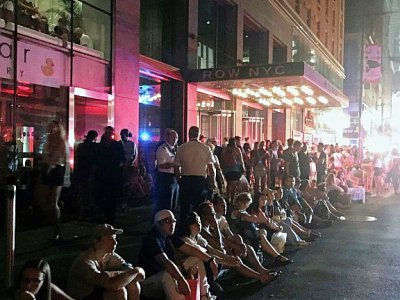 Des clients de l'hôtel Row NYC à Manhattan attendent sur le trottoir après une panne d'électricité géante - Thomas URBAIN [AFP]