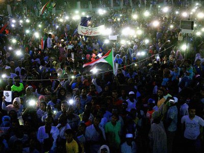 Des manifestants allument des bougies en hommage aux personnes tuées lors de la dispersion d'un sit-in, le 13 juillet 2019 à Khartoum - EBRAHIM HAMID [AFP]