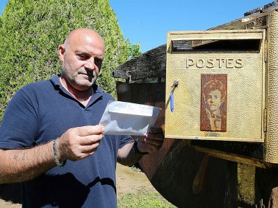 Bernard Colin, le gardien du cimetière de l'Ouest à Charleville-Mézières depuis 37 ans, sort une lettre de la boîte aux lettres dédiée au poète Arthur Rimbaud, le 21 juin 2019 - FRANCOIS NASCIMBENI [AFP]