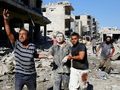 Accompagné de deux hommes, un Syrien sort des décombres d'un immeuble visé par un bombardement, à Maaret al-Noomane, dans le nord-ouest de la Syrie, le 22 juillet 2019 - Abdulaziz KETAZ [AFP]