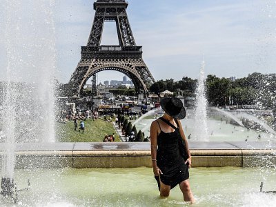 Une femme se rafraîchit dans les fontaines du Trocadéro près de la Tour Eiffel à Paris, le 22 juillet 2019 - ALAIN JOCARD [AFP]