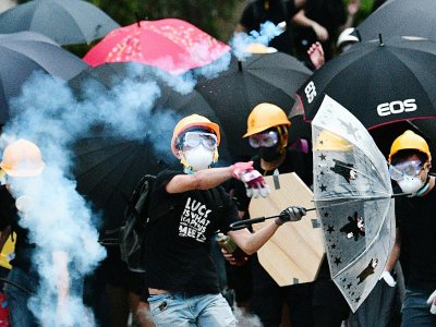 Un manifestant hongkongais renvoie vers la police une cartouche de gaz lacrymogène qui vient d'être tirée, à Yen Long le 27 juillet 2019 - Anthony WALLACE [AFP]