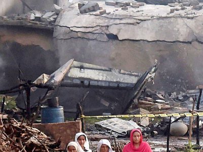 Des habitants passent près de la carcasse d'un avion de l'armée pakistanaise qui s'est écrasé sur une zone résidentielle à Rawalpindi (Pakistan) le 30 juillet 2019 - AAMIR QURESHI [AFP]