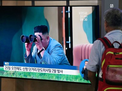 Un homme regarde à la télévision les images du dirigeant nord-coréen Kim Jong Un suivant avec des jumelles le tir de missiles balistiques nord-coréens, le 31 juillet 2019 dans une gare de Séoul, en Corée du Sud - Jung Yeon-je [AFP]