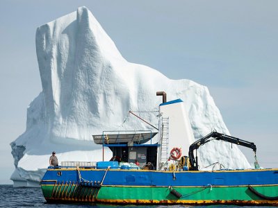 Le capitaine Edward Kean se tient sur son bateau devant un iceberg dans la baie de Bonavista, au large de Terre-Neuve, au Canada, le 29 juin 2019 - Johannes EISELE [AFP]