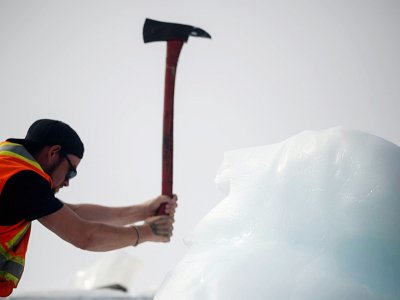 Le marin Taylor Lindsorn réduit en morceaux un bloc de glace d'iceberg dans la baie de Bonavista, au large de Terre-Neuve, au Canada, le 30 juin 2019 - Johannes EISELE [AFP]