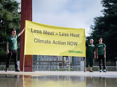 "Moins de viande = moins de chaleur, Action pour le climat maintenant" sur une banderole brandie par des militants de Greenpeace, le 8 août 2019 à Genève, avant la publication du rapport du Giec sur le climat et les terres - FABRICE COFFRINI [AFP]