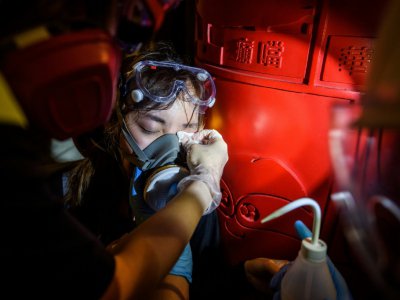 Une jeune femme qui a reçu des gaz lacrymogènes est prise en charge par des secouristes volontaires lors des manifestations pro-démocratie, le 3 août 2019 à Hong Kong - ANTHONY WALLACE [AFP]