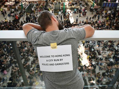 "Bienvenue à Hong Kong, une ville dirigée par la police et les gangsters", peut-on lire sur une affichette: des centaines de manifestants prodémocratie ont entamé le 9 août 2019 un sit-in à l'aéroport de la mégapole - Anthony WALLACE [AFP]