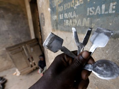 Un homme tient les instruments servant à réaliser les scarifications rituelles à Ibadan, dans le sud-ouest du Nigeria - PIUS UTOMI EKPEI [AFP]