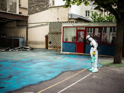 Un employé pulvérise un gel sur le sol de la cour de l'école Saint-Benoît, près de Notre-Dame de Paris, pour réduire les risques de contamination au plomb, le 8 août 2019 - Martin BUREAU [AFP/Archives]