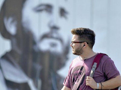 Un homme dans une rue à Cuba près d'un portrait de Fidel Castro le 16 juillet 2019 - YAMIL LAGE [AFP]