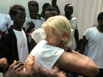 Une infirmière de MSF enlace un migrant à bord du navire Ocean Viking le 23 août 2019, pour célébrer l'annonce d'un prochain débarquement à Malte. - Anne CHAON [AFP]