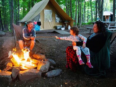 Une famille autour d'un feu de camp devant leur tente du camping Huttopia, le 14 août 2019 à Sutton, au Canada, - Sebastien St-Jean [AFP]