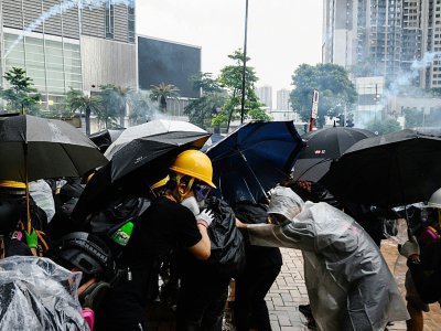 Des manifestants se protègent des gaz lacrymogènes tirés par la police, le 25 août 2019 à Hong Kong - Philip FONG [AFP]