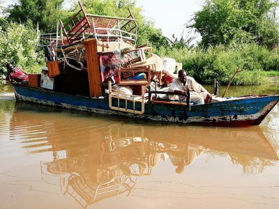Des Soudanais transportent leurs biens sur un bateau après des inondations dans le village de Wad Ramli, sur les rives du Nil, au nord de la capitale Khartoum, le 26 août 2019 - Ebrahim HAMID [AFP]