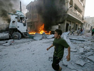 Un garçon court après qu'un  incendie s'est déclaré dans un bâtiment après un raid aérien du régime syrien contre la ville de Maaret al-Noomane dans la province d'Idleb (nord-ouest de la Syrie), le 28 août 2019 - Abdulazez Ketaz [AFP]