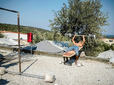 Un migrant fait de l'exercice devant sa tente près du camp de réfugiés de Moria, sur l'île grecque de Lesbos, le 1er septembre 2019 - ANGELOS TZORTZINIS [AFP]