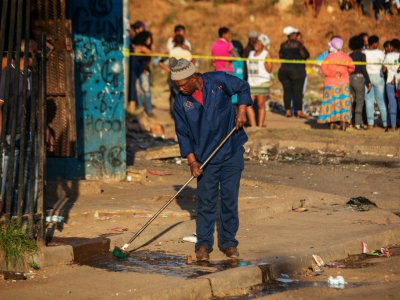 Un homme nettoie le 3 septembre 2019 à Johannesburg un trottoir tâché du sang de l'une des victimes des violences xénophobes en Afrique du Sud - Michele Spatari [AFP]