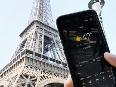 Une personne près de la Tour Eiffel tient son smartphone indiquant la température de 42 degrés Celsius, le 25 juillet 2019 à Paris - Bertrand GUAY [AFP/Archives]