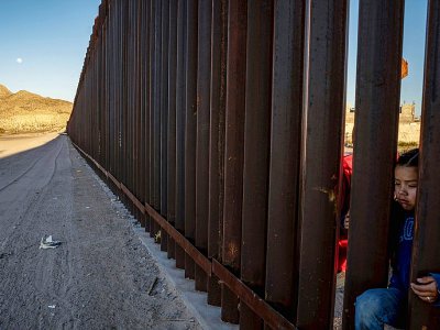 Une enfant passe la tête dans une portion de la barrière frontalière contruite entre le Mexique et les Etats-Unis, le 19 mars 2019 à Anapra (Nouveau-Mexique) - Paul Ratje [AFP/Archives]
