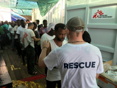 Un membre de l'équipe de sauvetage de l'Ocean Viking parle avec un migrant à bord du navire humanitaire, le 21 août 2019 - Anne CHAON [AFP/Archives]