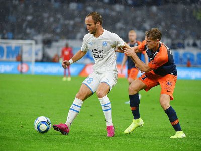 L'attaquant de Marseille Valère Germain (g) à la lutte avec le défenseur de Montpellier Nicolas Cozza, le 21 septembre 2019 à Marseille - SYLVAIN THOMAS [AFP]