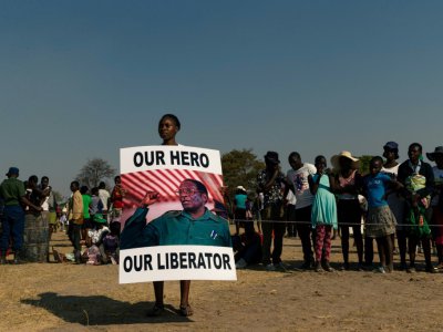 Une jeune femme tient une affiche où l'on peut lire: "Notre héro, notre libérateur" avec la photo de Mugabe le 16 septembre 2019 à Murombedzi - Jekesai NJIKIZANA [AFP]