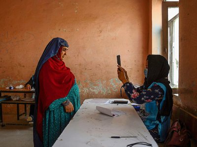 Une responsable de bureau de vote scanne avec un appareil biométrique une électrice, à Mazar-i-Shraif en Afghanistan, le 28 septembre 2019 pour l'élection présidentielle - FARSHAD USYAN [AFP]