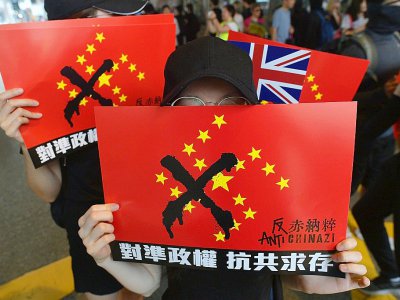 Des manifestants brandissent des drapeaux chinois où les étoiles ont été disposées en croix gammée, à Hong Kong le 29 septembre 2019 - Nicolas ASFOURI [AFP]