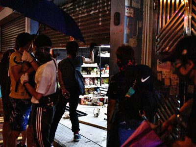 Des manifestants devant l'entrée d'un supermarché vandalisé, le 5 octobre 2019 à Hong Kong - Anthony WALLACE [AFP]