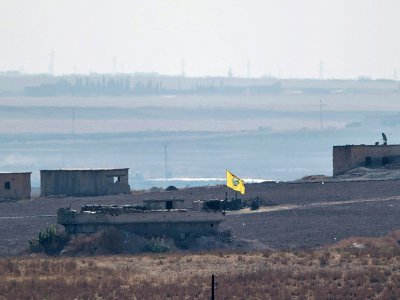 Le drapeau des Unités de protection du peuple (YPG) flottant au-dessus d'un bâtiment près de la ville syrienne de Tal Abyad, le 8 octobre 2019 - BULENT KILIC [AFP]