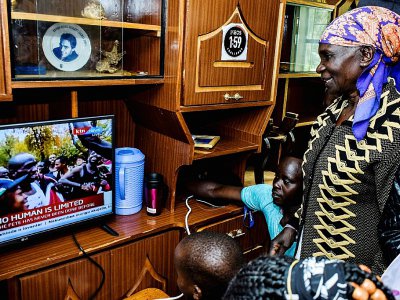 La mère du Kenyan Eliud Kipchoge, Janet Rotich (d), devant sa télévision, à Kapsisisywa au Kenya, le 12 octobre 2019 - BRIAN ONGORO [AFP]
