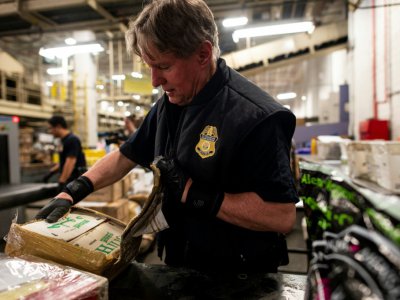 Un douanier trouve des pilules estampillées oxycodone dans des paquets au centre de tri postal de l'aéroport  John F. Kennedy, le 24 juin 2019 à New York - Johannes EISELE [AFP]