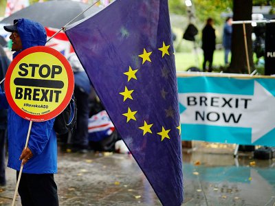 Un manifestant anti-Brexit porte un panneau et un drapeau européen devant le Parlement britannique à Londres, le 17 octobre 2019 - Tolga Akmen [AFP]