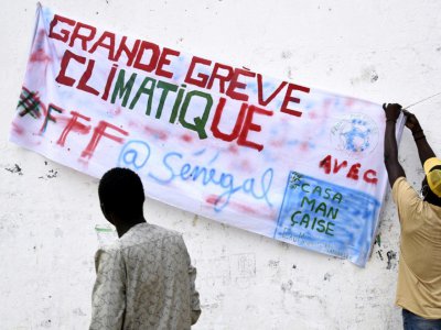 Un manifestant accroche une banderole "grande grève climatique" à l'occasion de la mobilisation pour le climat, le 20 septembre 2019 à Thiès, au Sénégal - SEYLLOU [AFP/Archives]
