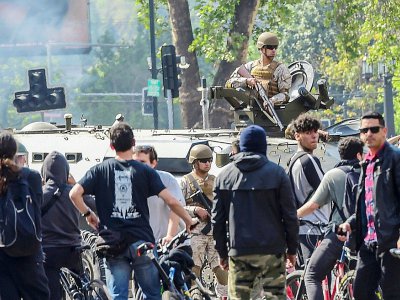 Un soldat chilien dans un char entouré par de manifestants à Santiago, le 19 octobre 2019 - MARTIN BERNETTI [AFP]