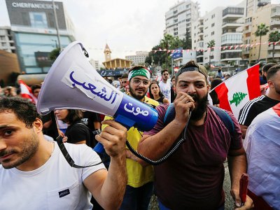 Mégaphone en main, des manifestants libanais défilent contre le pouvoir à Zouk Mosbeh, au nord de Beyrouth, le 20 octobre 2019 - JOSEPH EID [AFP]