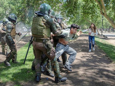 Des policiers arrêtent un manifestant durant des affrontements à Santiago, le 20 octobre 2019 - CLAUDIO REYES [AFP]