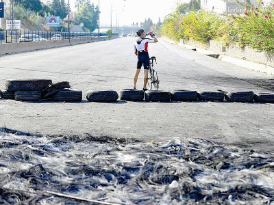 Un cycliste est photographié sur une route que des manifestants ont barré avec des pneus, à Byblos, au nord de Beyrouth, Liban, le  22 octobre 2019 - JOSEPH EID [AFP]