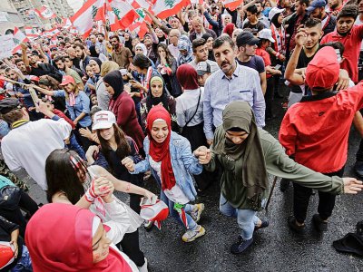 Des manifestants libanais dansent avec des drapeaux nationaux lors d'une manifestation sur la place al-Nour, à Tripoli dans le nord du pays, le 23 octobre 2019 - Ibrahim CHALHOUB [AFP]