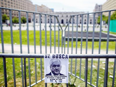 Une affichette avec un portrait du président chilien Sebastian Pinera accompagné de la mention "recherché", sur une grille de protection devant le palais présidentiel de La Moneda, à Santiago le 23 octobre 2019 - Pablo VERA [AFP]
