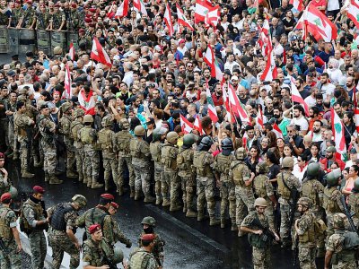 Des manifestants antigouvernementaux brandissent des drapeaux libanais face à l'armée à Jal al-Dib à la périphérie nord de Beyrouth, le 23 octobre 2019 - Anwar AMRO [AFP]