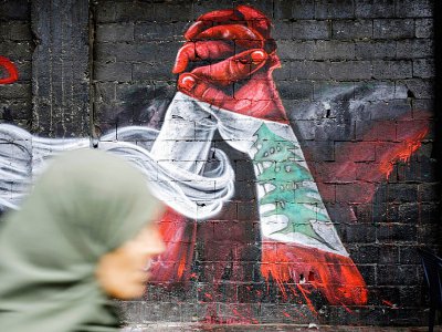 Une femme passe devant un graffiti à Tripoli dans le nord du Liban, le 24 octobre 2019 - Ibrahim CHALHOUB [AFP]