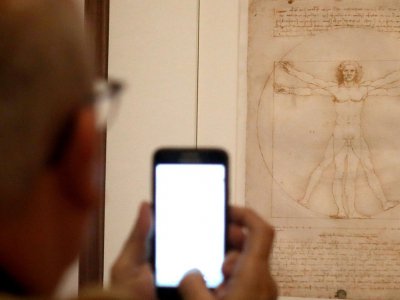Un visiteur photographie "L'homme de Vitruve" à l'ouverture de la grande rétrospective consacrée à Léonard de Vinci au Musée du Louvre, le 22 octobre 2019 à Paris - FRANCOIS GUILLOT [AFP]