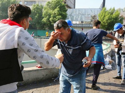Des manifestants irakiens se rincent les yeux après des tirs de gaz lacrymogène à Bagdad, le 26 octobre 2016 - - [AFP]